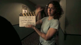 Woman holds a film clapboard in a movie theater hallway