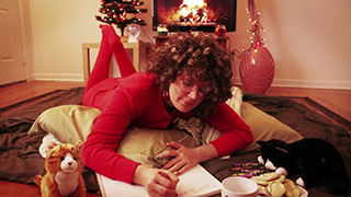 Woman wearing red pajamas writing a letter to Santa Claus