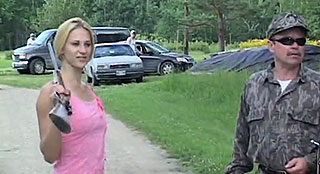 Pretty blonde woman holding a shotgun and a man dressed in camouflage