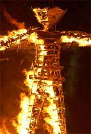 Burning Man sculpture on fire at night in the desert