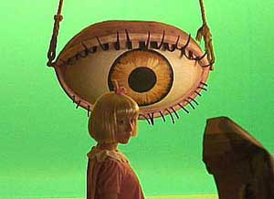 Young blond girl standing in front of a giant eyeball