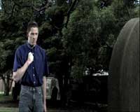 The Ancient Rite of Cory McGillis Young man standing in front of a grave at a cemetery