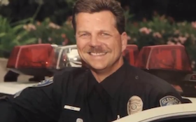 Ben Mihm smiles in his police uniform and cruiser