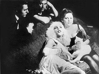 Mario Montez lies on a couch with a woman while Gerard Melanga and another man look on
