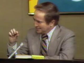 Talk show host Joe Franklin sits behind his desk on air