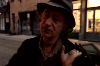 Jonas Mekas giving an interview while standing on Wooster St. in New York City