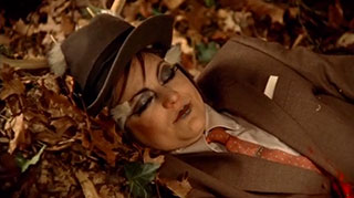 Woman dressed in a suit lying in the woods