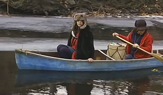 Man and a woman rowing a canoe down an icy river