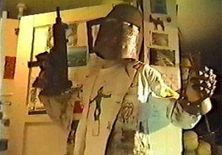 Guy wearing a metal helmet and iron glove while holding an uzi
