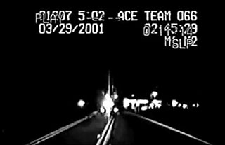 Grainy black and white footage of a police officer's dashboard camera
