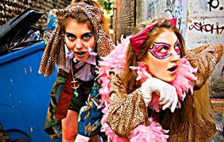 Two teenage girls dressed in colorful costumes running through an alley