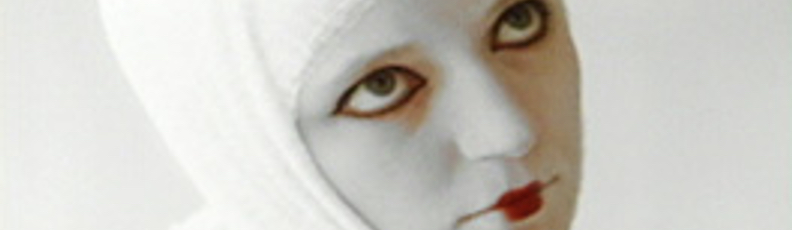 A bandaged Kristie Alshaibi wears intense white makeup in a still from the Usama Alshaibi film Convulsion Expulsion